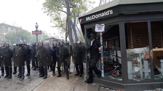 CRS riot police officials stand next to a damaged McDonalds resteraunt during a demonstration on the sidelines of a march for the annual May Day workers' rally in Paris on May 1, 2018.(AFP)