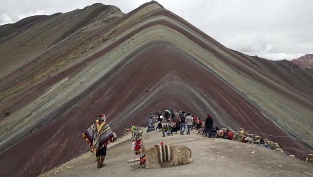 An Andean man rests with his llama on Rainbow Mountain in Pitumarca, Peru.(AP) An Andean man rests with his llama on Rainbow Mountain in Pitumarca, Peru.(AP)