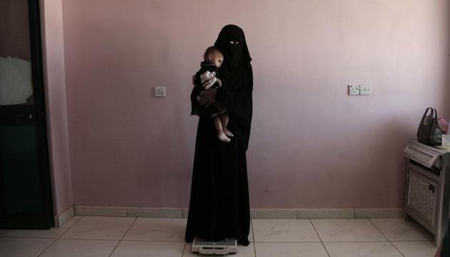 Umm Mizrah, a 25-year-old Yemeni woman, holds her son Mizrah on a scale in Al-Sadaqa Hospital in the southern Yemen city of Aden.(AP) Umm Mizrah, a 25-year-old Yemeni woman, holds her son Mizrah on a scale in Al-Sadaqa Hospital in the southern Yemen city of Aden.(AP)