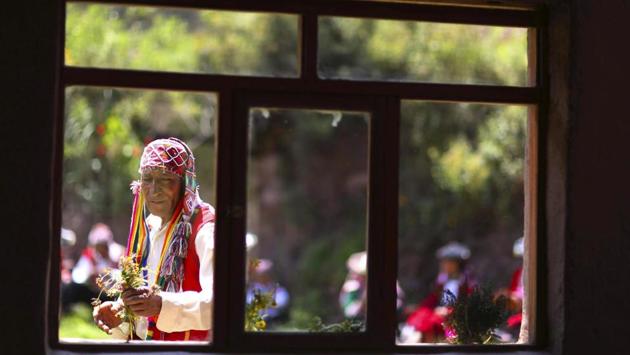 A former farmer who now sells Andean clothes collects flowers while he waits for tourists. The popularity of Rainbow Mountain, which attracts up to 1,000 visitors each day, has provided a much-needed economic jolt to this remote region populated by struggling alpaca herders. (Martin Mejia / AP) A former farmer who now sells Andean clothes collects flowers while he waits for tourists. The popularity of Rainbow Mountain, which attracts up to 1,000 visitors each day, has provided a much-needed economic jolt to this remote region populated by struggling alpaca herders. (Martin Mejia / AP)