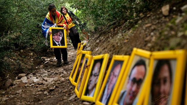 People pass on a portrait of Catalonia's ousted president Carles Puigdemont as they form a human chain in support of jailed and self-exiled Catalan politicians after hiking the Montserrat Mountain near Barcelona, Spain. (Pau Barena / AFP) People pass on a portrait of Catalonia's ousted president Carles Puigdemont as they form a human chain in support of jailed and self-exiled Catalan politicians after hiking the Montserrat Mountain near Barcelona, Spain. (Pau Barena / AFP)
