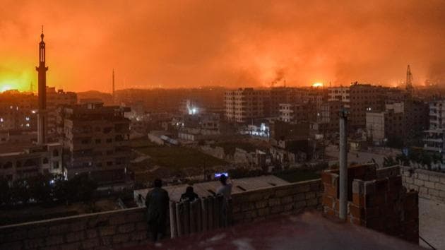 People stand on a roof to observe explosions in the skyline of a southern district of the Syrian capital Damascus, during regime strikes targeting the Islamic State group in the Palestinian camp of Yarmuk and neighbouring districts. (Rami al Sayed / AFP) People stand on a roof to observe explosions in the skyline of a southern district of the Syrian capital Damascus, during regime strikes targeting the Islamic State group in the Palestinian camp of Yarmuk and neighbouring districts. (Rami al Sayed / AFP)