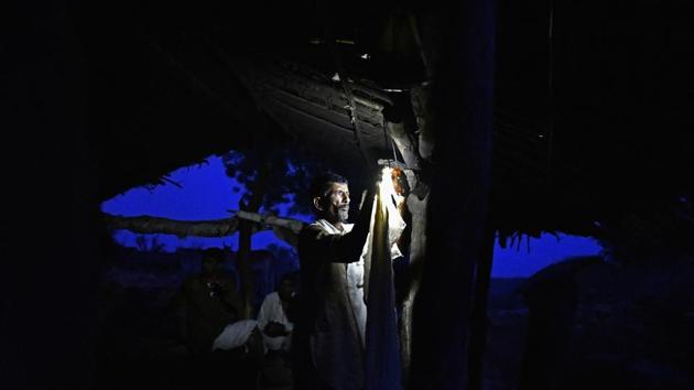 A man hangs a light-emitting diode (LED) lamp at a home in Kraska village, Rajasthan. Kraska falls under the critical tiger habitat (CTH) part of the core area of the Sariska Tiger Reserve. (Anindito Mukherjee / Bloomberg)