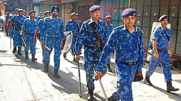 A poster declaring Yashwant Bobby a martyr; (right) a flag march by Rapid Action Force personnel, in Phagwara on Saturday.(HT photos)