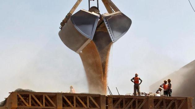 Workers stand as a crane loads wheat onto a ship at Mundra Port in Gujarat.(Reuters File Photo)