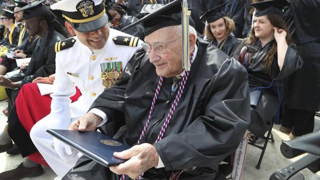 World War II veteran Bob Barger, assisted by Haraz Ghanbari, University of Toledo director of military and veteran affairs, left, smiles after receiving his diploma at the commencement ceremony at the university, Saturday, May 5, 2018, in Toledo, Ohio.(AP)