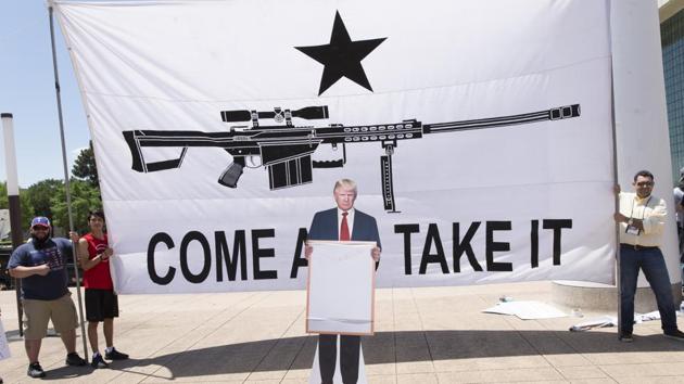 A cardboard cut-out of US President Donald Trump stands in front of a large banner that reads "Come And Take It," during a pro-gun rally on the sidelines of the National Rifle Association (NRA) annual meeting in Dallas, Texas, US, on Saturday, May 5, 2018.(Bloomberg)