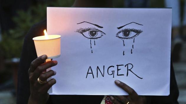 A protester holds a candle and placard seeking an end to sexual violence against women.(AP File Photo)