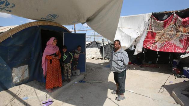 Displaced Iraqis stand outside a tent where they are taking shelter in a camp for internally displaced people near al-Khalidiyeh in Iraq's western Anbar province on April 24, 2018.(AFP)