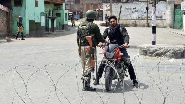 A security personnel stops a bike rider during curfew-like restrictions imposed to maintain law and order in Srinagar on Sunday.(PTI Photo)