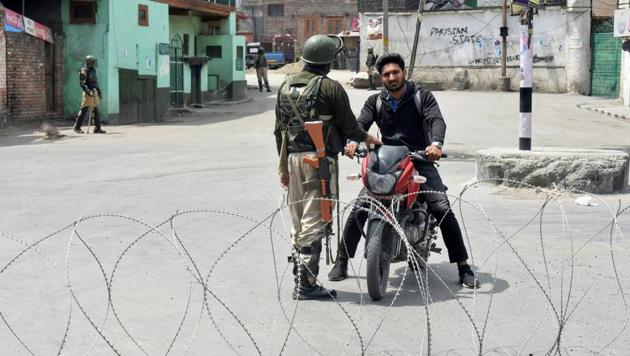 Security personnel stop a bike rider during curfew-like restrictions imposed to maintain law and order in Srinagar on Sunday. The authorities have put up barricades as well as concertina wires across the city in view of a protest march called by separatists.(PTI Photo)