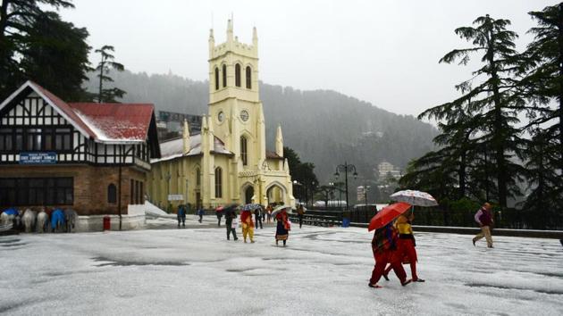 People take a stroll with umbrellas at Ridge as Shimla received hailstorm on Tuesday. Shimla and its surrounding areas were lashed by a severe hailstorm, throwing normal life out of gear. (Deepak Sansta/HT)