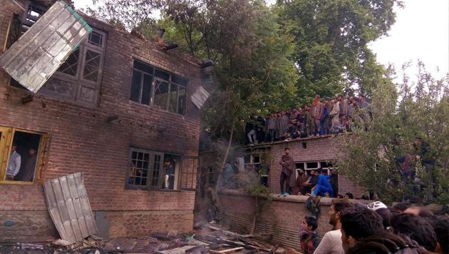 People look on the damaged house where militants were hiding, at Badigam in Shopian district of south Kashmir. (PTI Photo) People look on the damaged house where militants were hiding, at Badigam in Shopian district of south Kashmir. (PTI Photo)