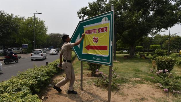 A policeman removes the poster of Maharana Pratap Road that was put up in place of the Akbar Road signboard in New Delhi.(Anushree Fadnavis / HT Photo)