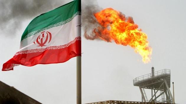 A gas flare on an oil production platform in the Soroush oil fields is seen alongside an Iranian flag in the Persian Gulf, Iran. President Donald Trump’s decision to reimpose sanctions on Iran threatens to tighten global oil markets and could derail tens of billions of dollars in business deals.(Reuters File Photo)