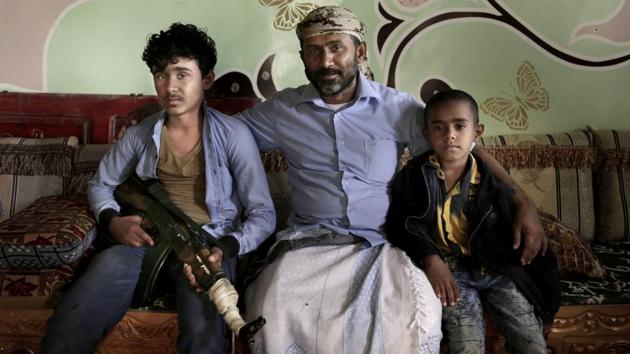 Ahmed al-Kawkabani (C), leader of the southern resistance unit in Hodeida with his 16-year-old son Shaeeb (L) and his 8-year-old Abdullah, at their home. He said his son wants to join him and fight the war. Despite his advise to concentrate more on his studies, Shaeeb finishes school, changes from his uniform and takes up a rifle. (Nariman El-Mofty / AP) 