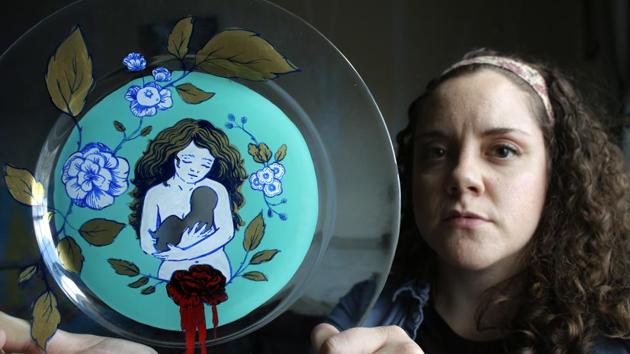 Artist Ashley MacLure holds her painting "The Dream" created from acrylic paint and colour marker on a glass plate. The blank space at the centre is meant to represent the absence of a child due to a miscarriage. (AP) Artist Ashley MacLure holds her painting "The Dream" created from acrylic paint and colour marker on a glass plate. The blank space at the centre is meant to represent the absence of a child due to a miscarriage. (AP)