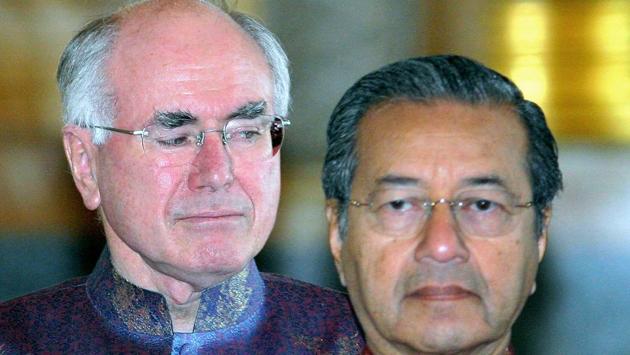 Then Australian Prime Minister John Howard stares at Mahathir Mohamad as the Asia-Pacific Economic Cooperation leaders meet in Bangkok on October 21, 2003. Long critical of Australia’s participation, Mahathir said in December 2002: “This country stands out like a sore thumb trying to impose its European values in Asia as if the good old days when people can shoot Aborigines without caring about human rights.” (Luis Enrique Ascui / Getty Images File)