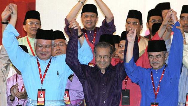 Mahathir Mohamad (C), with then Prime Minister Abdullah Ahmad Badawi (R), and Deputy PM Najib Razak at the UMNO general assembly. Even after stepping down, he remained influential, smoothing Najib’s ascent to the top in 2009 after criticizing his first successor, Badawi, for poor economic management. He also supported Najib in the 2013 elections, eventually becoming his most ferocious critic. (Lai Seng Sin / AP)