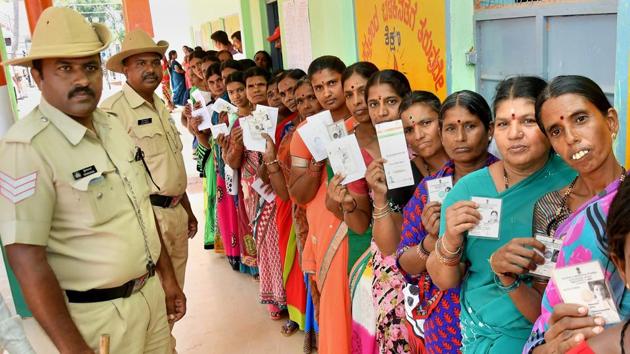 Voters stand in a queue with their voting IDs at a polling booth during the Karnataka assembly elections 2018, at Hundi village in Mysore on Saturday.(PTI)