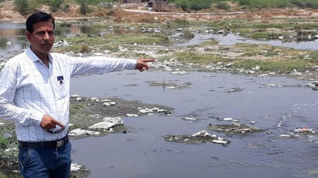 Mahaveer Singh Sukarlai, who founded the Sri Kisan Paryavaran Sangharsh Samiti, points at the polluted Bandi River.(HT Photo) Mahaveer Singh Sukarlai, who founded the Sri Kisan Paryavaran Sangharsh Samiti, points at the polluted Bandi River.(HT Photo)