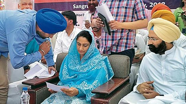 Union food processing industries minister Harsimrat Kaur Badal reviews a document as Lehragaga MLA Parminder Dhindsa looks on in Sangrur on Sunday.(HT Photo)