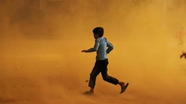 A boy runs for cover during a dust storm in New Delhi on Sunday. The Met office has forecast more storms till Tuesday.(Reuters photo)