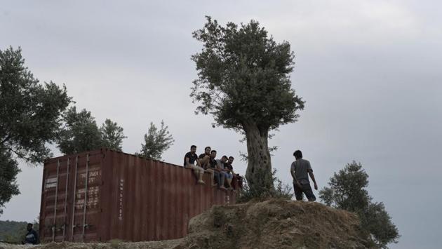 Refugees and migrants sit on the top of a container at a makeshift camp on the northeastern Aegean island of Lesbos. Meanwhile, to try to bypass the islands, an even higher number of migrants and refugees are now crossing Greece’s heavily militarized land border with Turkey in the northeast of the country. (Petros Giannakouris / AP) 