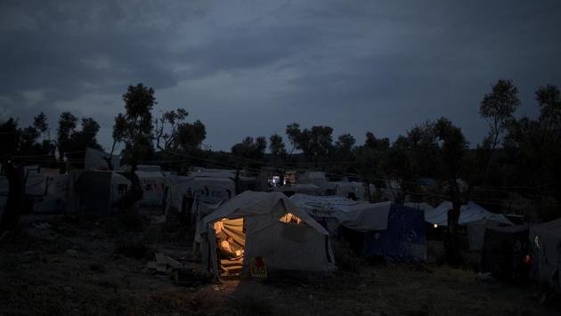 A Syrian man reads inside his tent outside Moria. Currently, asylum seekers on five Aegean Sea islands — Lesbos, Chios, Samos, Leros, and Kos — are banned from travelling on to the Greek mainland as part of the EU’s “containment policy.” That’s causing severe overcrowding at the islands’ camps, and the government has faced legal challenges and protests against the measure. (Petros Giannakouris / AP) 