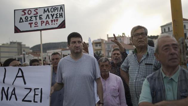 Islanders hold a placard which reads in Greek “SOS Moria. Solution now”, in a protest during a visit by Greek Prime Minister Alexis Tsipras. Residents complain about petty crimes that have risen since the camps opened, and others say their good will toward people fleeing war had been exploited by Greek and European policymakers. (Petros Giannakouris / AP) 
