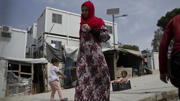 Children play as a woman walks inside the camp at Moria. The Greek parliament is now debating draft legislation aimed at easing pressure on the islands. Under the proposal, migrants would be allowed to move to camps on the Greek mainland, but they would remain under restriction and could be banned from leaving the regions of the country where they are placed. (Petros Giannakouris / AP) 