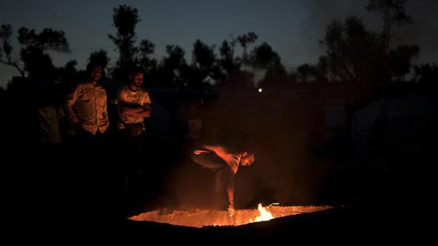 Refugees burn garbage in an old Greek army machine-gun nest. Spread over a hillside, Moria’s shoebox-shaped trailers and tents are home to refugees from Syria, Iraq, Congo, and over 50 other regions of war and hardship. The camp, crowded but still generally kept in good order, spills into the neighbouring fields, where asylum seekers — mostly African men — have little hope of leaving. (Petros Giannakouris / AP) 
