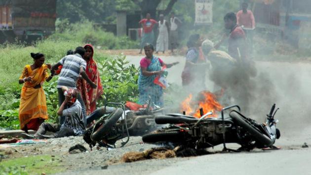People injured in poll violence sit by the side of a road as a vehicle is set on fire during the panchayat polls, in Nadia district of West Bengal.(PTI File Photo)