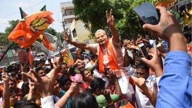 A supporter of Bharatiya Janata Party (BJP) wearing a mask of Prime Minister Narendra Modi flashes victory sign as he celebrates early leads for the party in the Karnataka state elections in Bengaluru. The BJP has taken a big lead over the Congress in the Karnataka election results and touched the halfway mark by noon, counting of votes showed on Tuesday. (Arijit Sen / HT Photo)