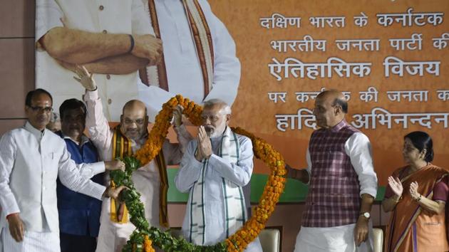 Prime Minister Narendra Modi (C) gestures after being presented a garland as (L-R) MP chief minister Shivraj Singh Chouhan, transport minister Nitin Gadkari, BJP president Amit Shah, home minister Rajnath Singh and foreign minister Sushma Swaraj look on at a ceremony after the Karnataka election results, at the BJP headquarters in New Delhi on May 15, 2018.(Vipin Kumar/HT Photo)