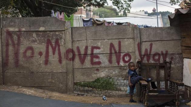 A toddler stands in front of a graffitied wall at an abandoned building occupied by squatters in downtown Johannesburg, South Africa. The city wants squatters cleared out to make way for an urban revival, with proposals to expropriate buildings and turn them over to private developers. (Bram Janssen / AP) A toddler stands in front of a graffitied wall at an abandoned building occupied by squatters in downtown Johannesburg, South Africa. The city wants squatters cleared out to make way for an urban revival, with proposals to expropriate buildings and turn them over to private developers. (Bram Janssen / AP)