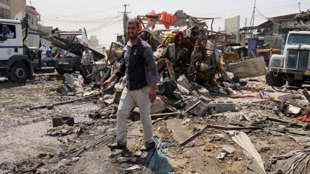 Iraqis look at the damage following a car bomb explosion in Baghdad.(AFP File Photo)