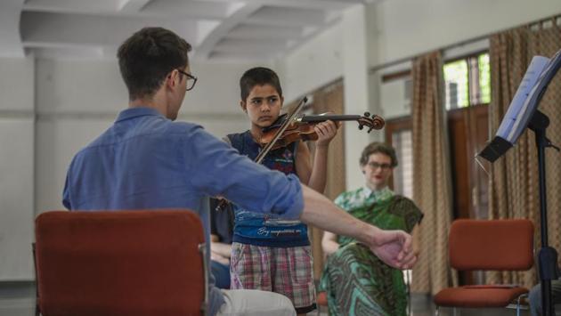 Muskaan, a student takes up the violin during a lesson at the residential quarters of Ministry of External Affairs. The initiative is using music as an aid to building confidence and a deeper awareness of culture for the holistic development of the children and their community. (Burhaan Kinu / HT Photo)