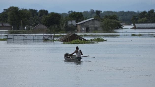 A man moves on a boat near submerged houses near Kaziranga national park in Assam.(AP File Photo)