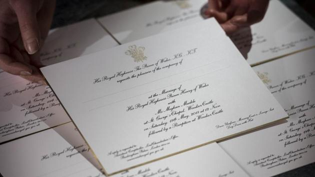 Hands hold freshly printed invitations for Prince Harry and Meghan Markle's wedding at a workshop of Barnard and Westwood who have held the Royal Warrant for Printing and Bookbinding since 1943. Using American ink on English card, the invitations were printed in gold and black, then burnished and gilded around the edge. (Victoria Jones / WPA Pool / Getty Images)