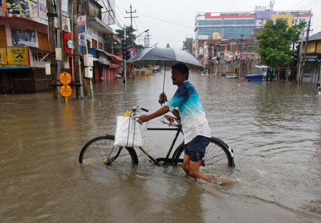 People walk through a waterlogged street after heavy rainfall in Agartala on Friday. At least four people, including a child and a woman, were killed early on Friday in mud house collapses in two incidents in West Tripura district of Tripura after the downpour. (Jayanta Dey / REUTERS) People walk through a waterlogged street after heavy rainfall in Agartala on Friday. At least four people, including a child and a woman, were killed early on Friday in mud house collapses in two incidents in West Tripura district of Tripura after the downpour. (Jayanta Dey / REUTERS)
