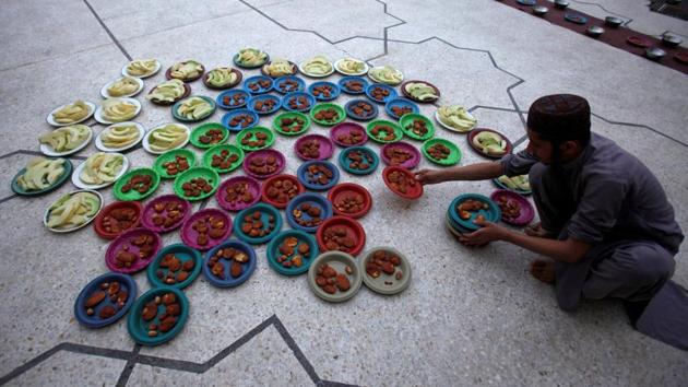 A man arranges food plates for iftar at a mosque in Peshawar, Pakistan. Muslims traditionally break their fast like the Prophet Muhammad did some 1,400 years ago, with a sip of water and some dates at sunset. (Fayaz Aziz / REUTERS) 