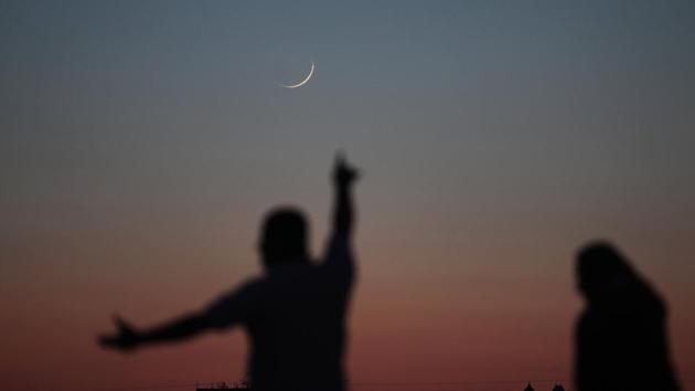A Palestinian man points towards the moon in its Crescent form in Khan Yunis in the southern Gaza Strip. Once the start of the holy month is declared, Muslims share greetings such as “Ramadan kareem” and “Ramadan mubarak” via text messages, calls and emails to family and friends. (Said Khatib / AFP) 