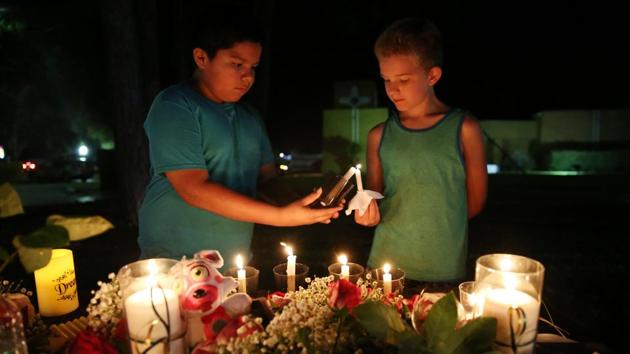 Christian Cardenas 10, helps Jaydon Johnson 8, light a candle during a vigil for the victims of a shooting at Santa Fe High School that left several dead and injured in Santa Fe, Texas, U.S., May 18, 2018.(REUTERS)