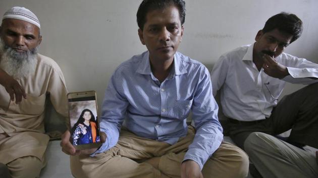 Abdul Aziz Sheikh, center, father of Sabika Sheikh, a victim of a shooting at a Texas high school, shows a picture of his daughter in Karachi, Pakistan, Saturday, May 19, 2018.(AP)