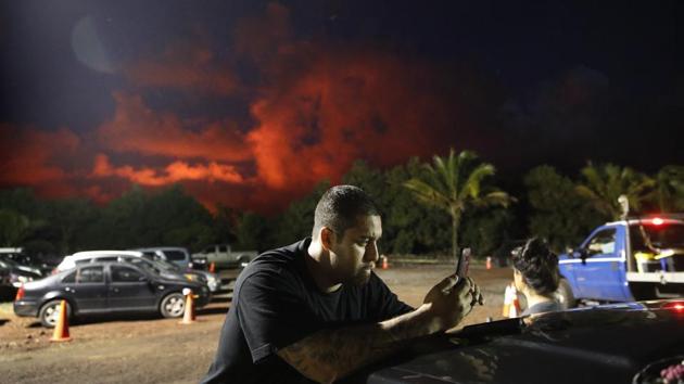 Evacuee Michael Hauanao, 32, watches a clip on a phone showing volcanic activity at a makeshift donation centre as clouds turn red from lava flow in the Leilani Estates subdivision. Lava flows have picked up speed in recent days, spattering molten rock that hit a man in the leg. (Jae C. Hong / AP) Evacuee Michael Hauanao, 32, watches a clip on a phone showing volcanic activity at a makeshift donation centre as clouds turn red from lava flow in the Leilani Estates subdivision. Lava flows have picked up speed in recent days, spattering molten rock that hit a man in the leg. (Jae C. Hong / AP)