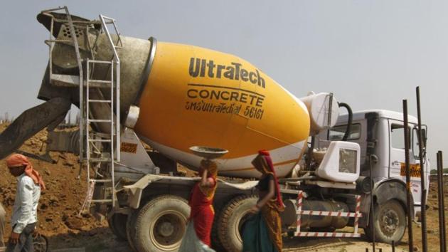 Workers walk in front of an UltraTech concrete mixture truck at the construction site of a commercial complex in Ahmedabad.(Reuters File Photo)