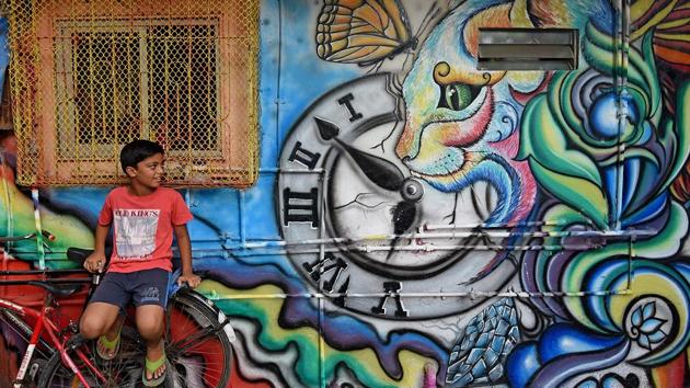 A boy sits on a bicycle next to a newly painted house in a slum at Khar Danda in Mumbai. Houses and shops in the slum colony were painted in the second week of May. (Satyabrata Tripathy/HT Photo)