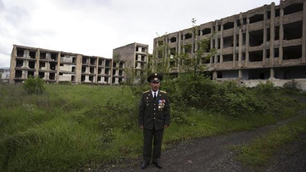 Armenian Garnik Avanesyan, veteran Lieutenant Colonel poses in front of buildings destroyed during the war in Shusha town. Nagorno-Karabakh has been under the control of ethnic Armenian forces backed by Armenia since the end of a 1994 war. Armenia’s new government has raised hopes here that a breakthrough could come, or at least bring more investment. (Thanassis Stavrakis / AP) Armenian Garnik Avanesyan, veteran Lieutenant Colonel poses in front of buildings destroyed during the war in Shusha town. Nagorno-Karabakh has been under the control of ethnic Armenian forces backed by Armenia since the end of a 1994 war. Armenia’s new government has raised hopes here that a breakthrough could come, or at least bring more investment. (Thanassis Stavrakis / AP)