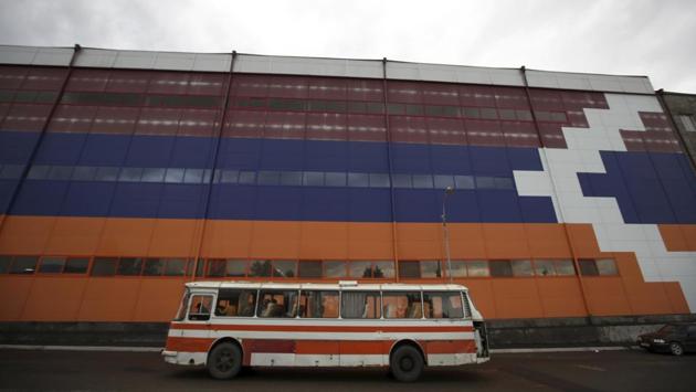 A bus passes in front of a factory painted with the colors of the self-proclaimed Republic of Artsakh (formerly Nagorno-Karabakh) flag in the capital Stepanakert. Nagorno-Karabakh’s 150,000 people don’t hold Azerbaijan passports and can travel only to Armenia, unless they apply for Armenian passports. The mountainous region’s self-declared sovereignty isn’t recognized by any country. (Thanassis Stavrakis / AP) A bus passes in front of a factory painted with the colors of the self-proclaimed Republic of Artsakh (formerly Nagorno-Karabakh) flag in the capital Stepanakert. Nagorno-Karabakh’s 150,000 people don’t hold Azerbaijan passports and can travel only to Armenia, unless they apply for Armenian passports. The mountainous region’s self-declared sovereignty isn’t recognized by any country. (Thanassis Stavrakis / AP)